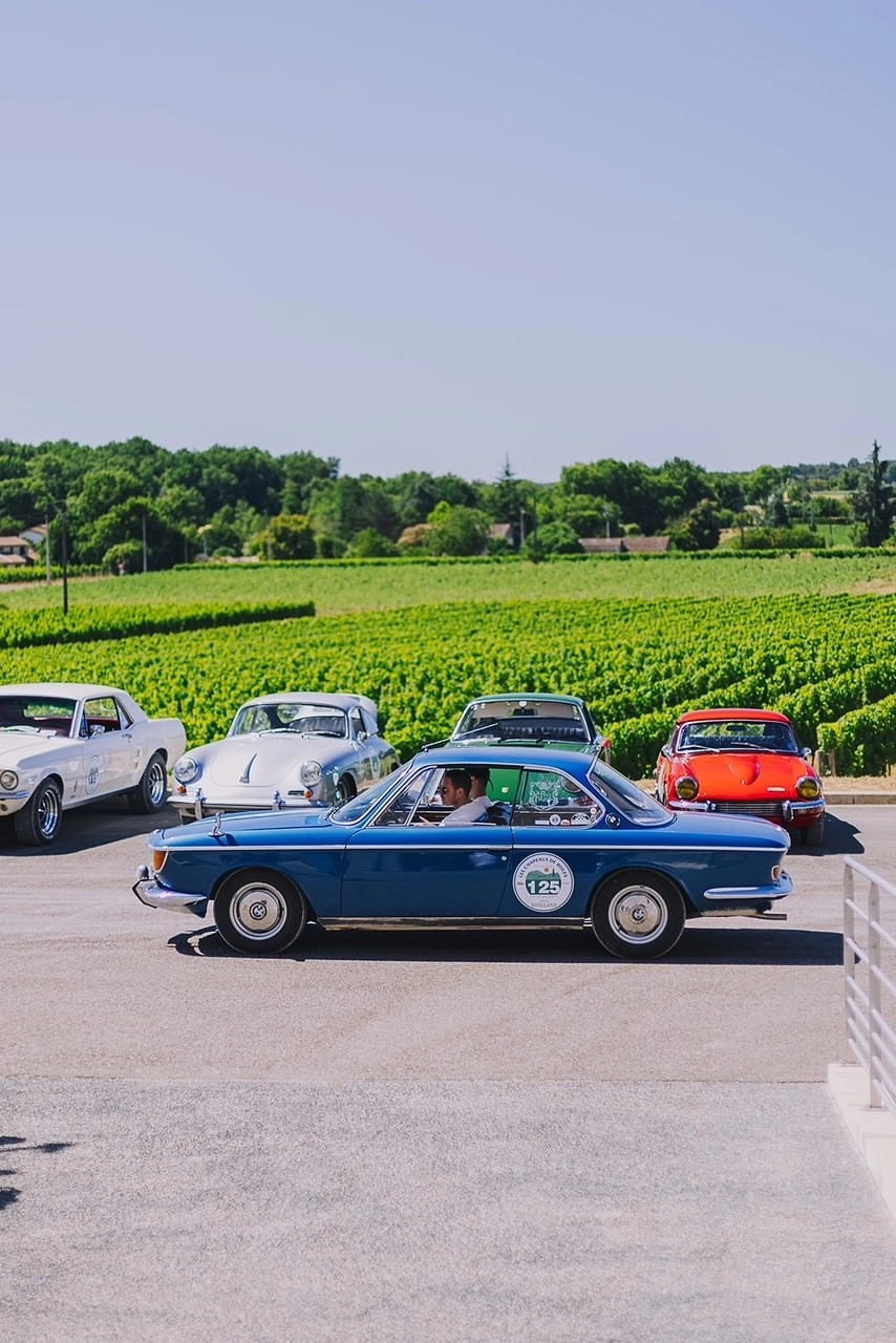 Un coupé BMW ancien sur les coteaux de Saint-Émilion, entre vignes et pierre dorée.